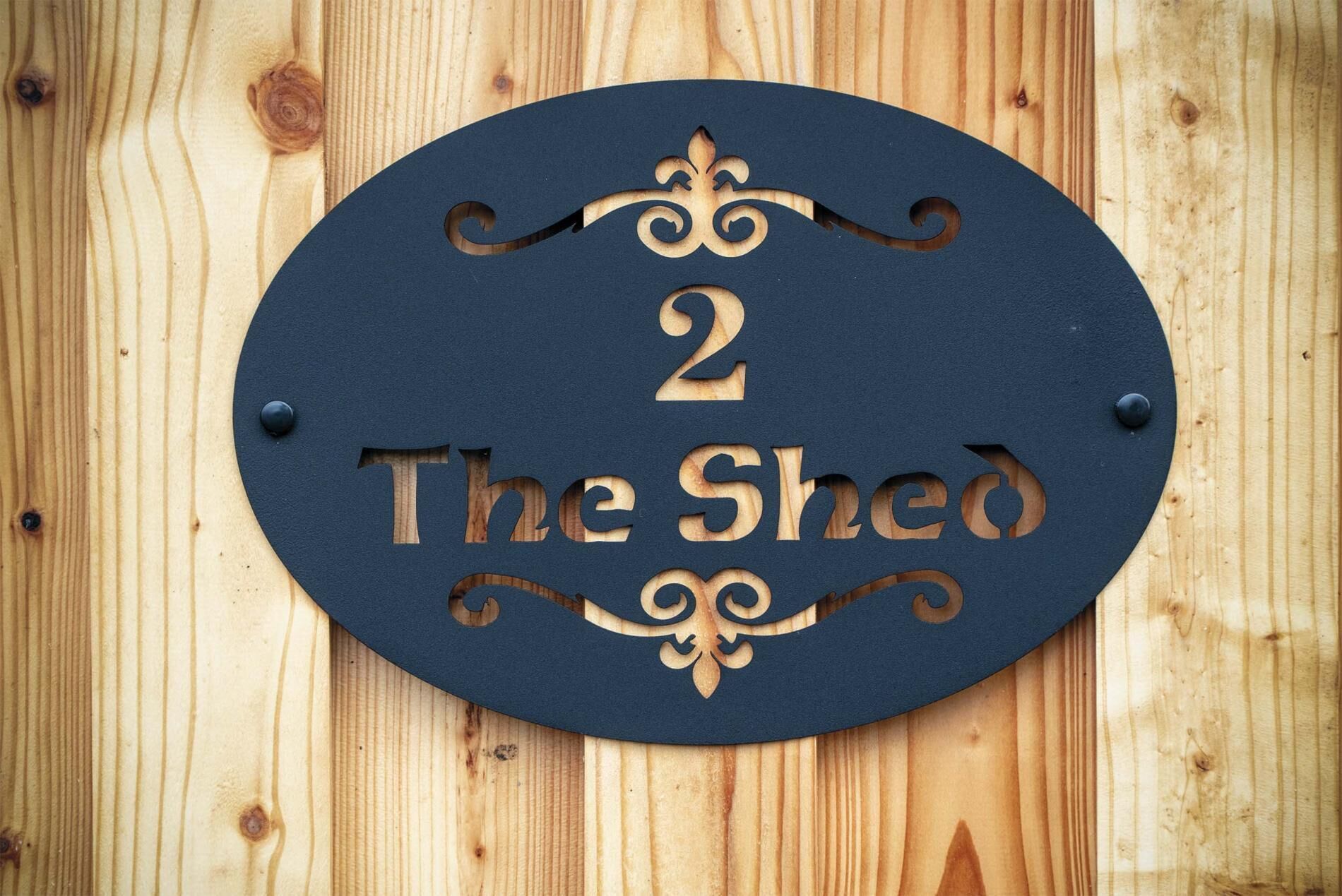 Een houten bord met het cijfer 2 en de woorden 'The Shed' erin gekerfd.