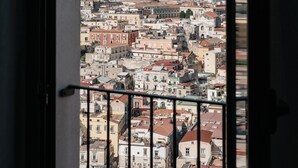 A view through an arched window of a cityscape with buildings and a distant mountain range. - Vista Napoli Residence (Naples)