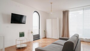 A modern living room with a grey sofa, a flat-screen TV, a round side table, and a white wardrobe. - Vista Napoli Residence (Naples)