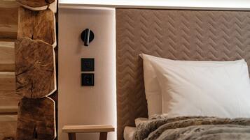 Un dormitorio moderno con pared de madera, una cama con cabecera acolchada y un panel de control junto a la cama.