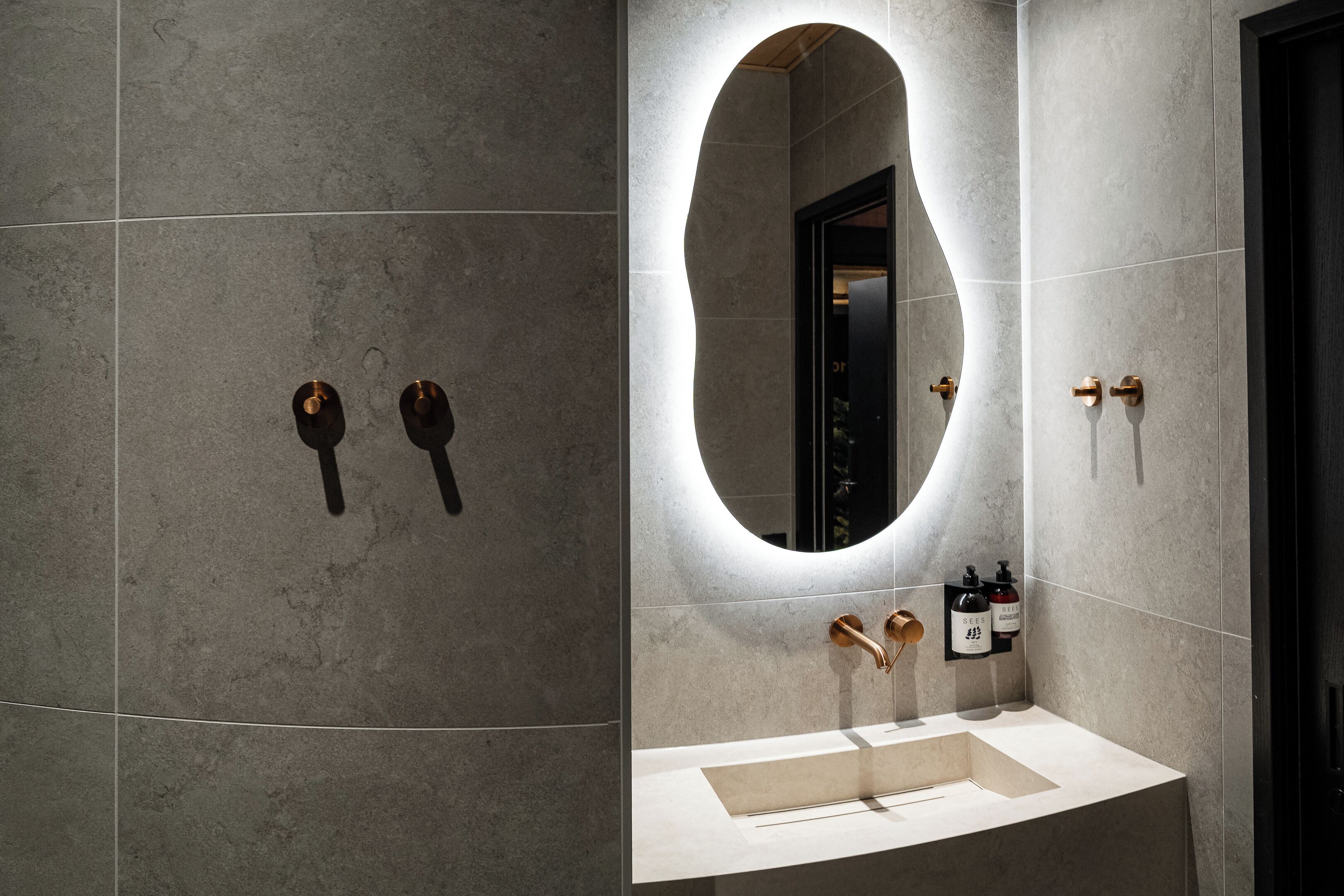 A modern bathroom with a large mirror, a sink, and two towel dispensers.