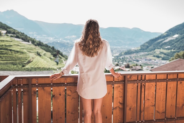 A person standing on a balcony overlooking a mountainous landscape.