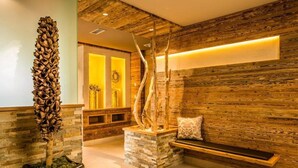 A reception area with a wooden wall, a bench, and a decorative tree sculpture. - Hotel am Sonneck (Lagundo)