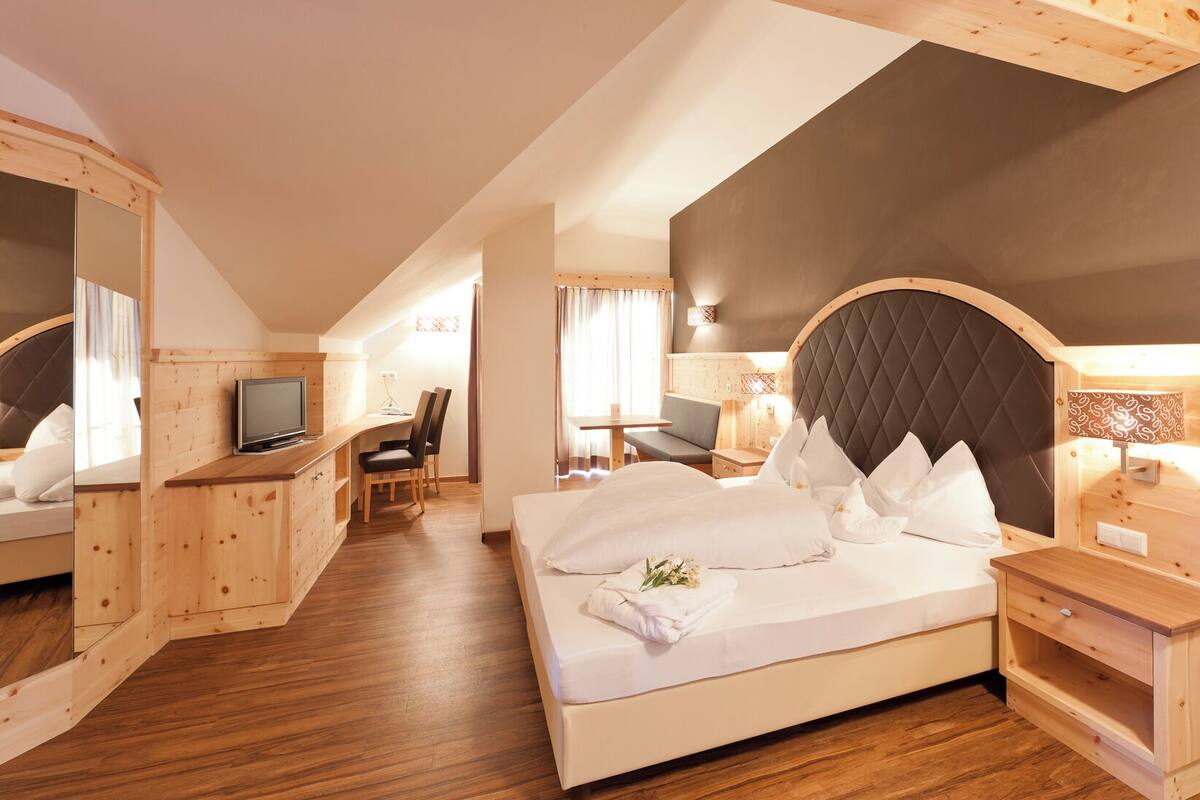 A hotel room with a large bed, a desk, a television, and a seating area.