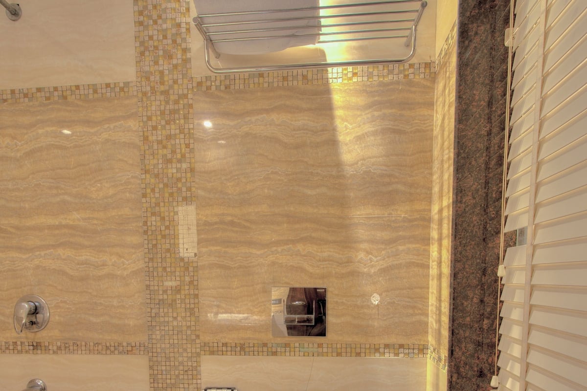 A bathroom with a marble floor, a toilet, a shower area, and a towel rack.