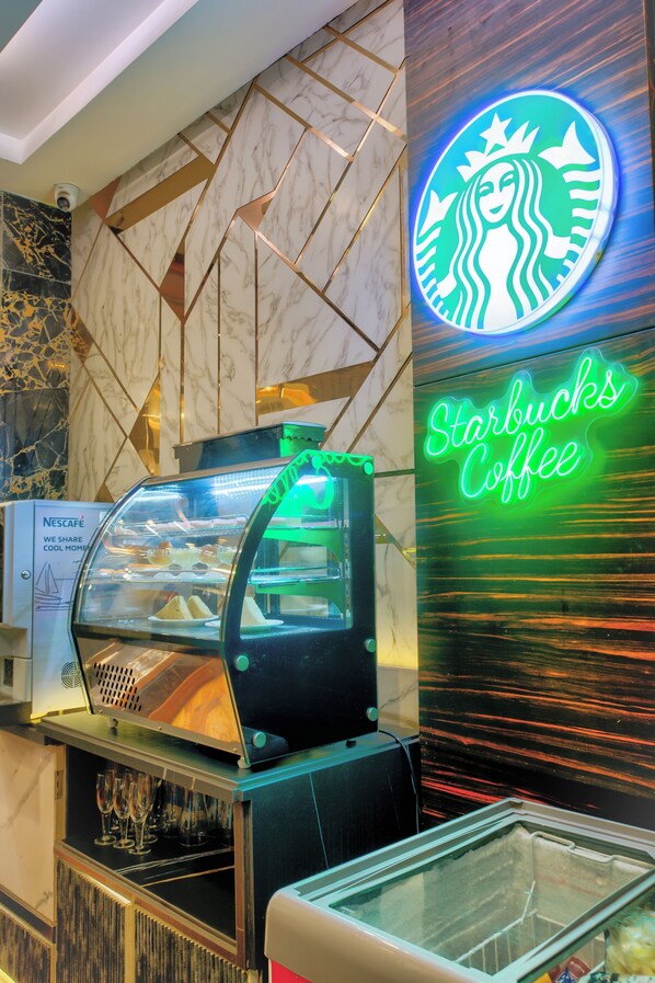 A Starbucks Coffee sign, a coffee machine, and a display case with glasses.