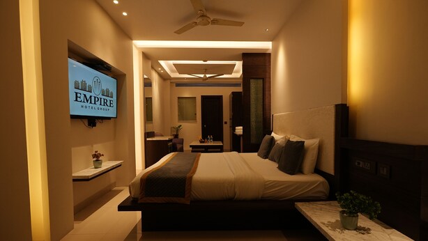 Una habitación de hotel moderna con cama, mesita de noche, televisor y ventilador de techo.