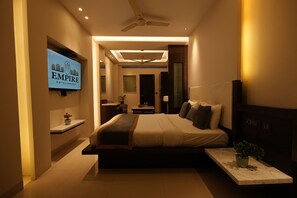 A modern hotel room with a bed, bedside table, TV, and a ceiling fan.