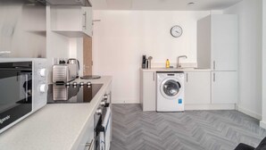 A compact kitchen with a microwave, toaster, and washing machine.