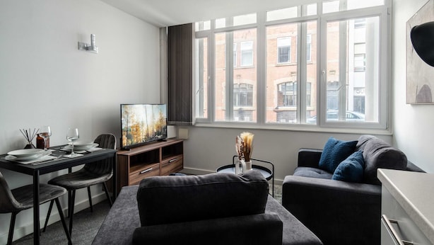 A modern living room with a dining area, large windows, and a city view.