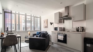 A modern kitchen with a dining area, a sofa, and a view of the city.