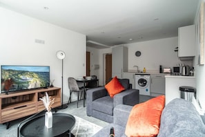 Cozy living space with a flat-screen TV, sofa, and kitchen area.