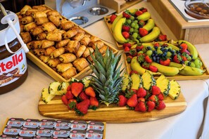 A buffet with pastries, fruits, and yogurt parfaits.