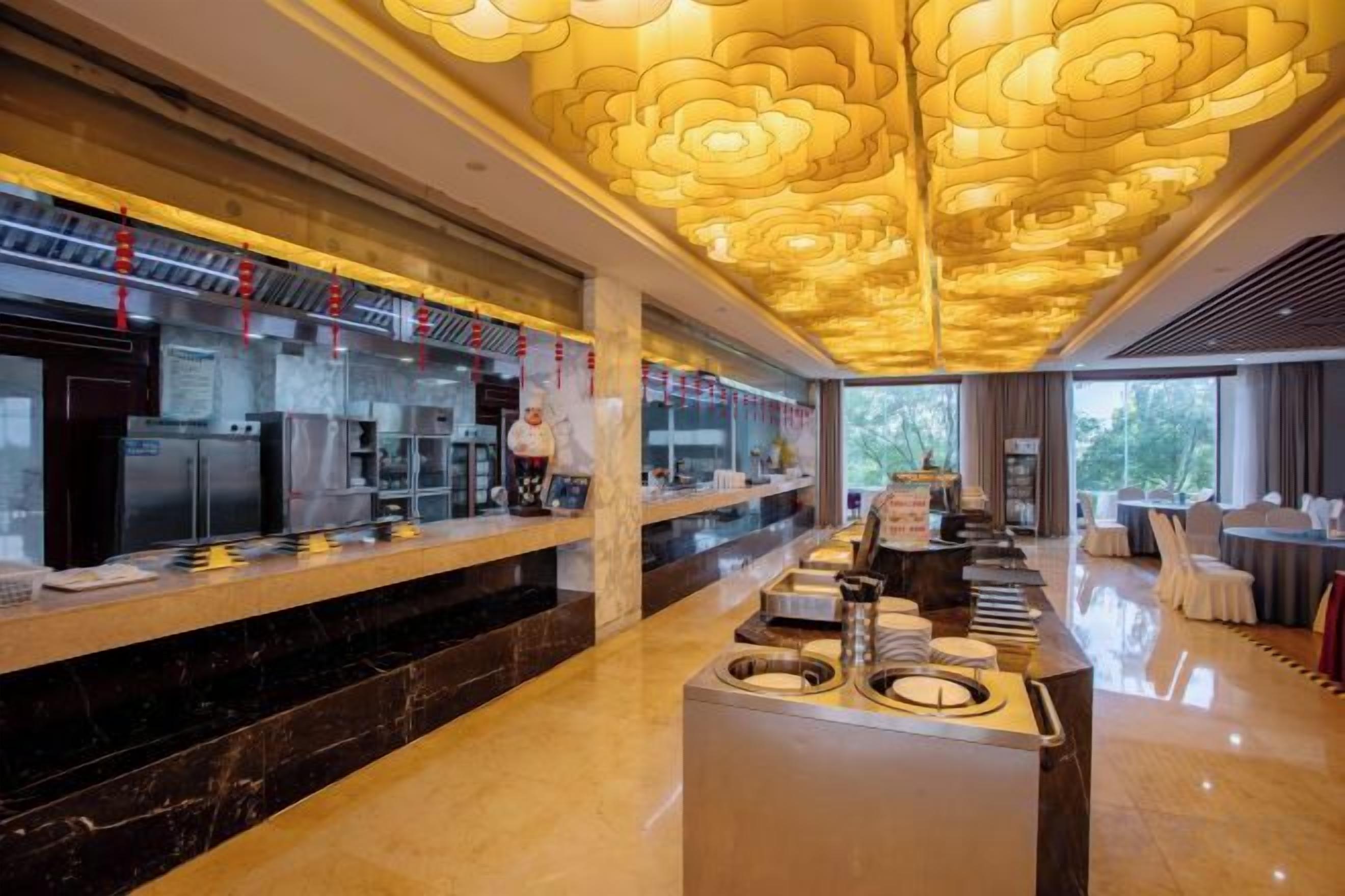 A modern kitchen area with a marble countertop, a central island, and a ceiling with a floral light fixture.