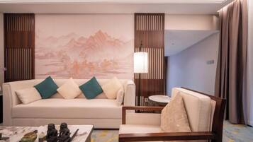 A hotel room with a sofa, armchair, and a table with decorative items.