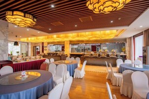 Un salón de banquetes con mesas redondas, sillas blancas y una zona de bar.