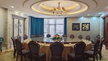 A conference room with a round table, chairs, a chandelier, and artwork on the walls.