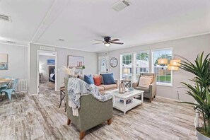 A spacious living area with a grey sofa, a coffee table, and a ceiling fan. - St Augustine Escape - 3-BR, WIFI, TV (St Augustine)