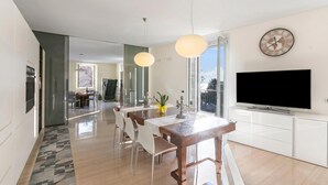 Eine moderne Küche mit Essbereich, einem großen Fenster und einem Flachbildfernseher.