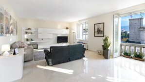 Ein modernes Wohnzimmer mit Sofa, Fernseher und Balkon mit Pflanzen.