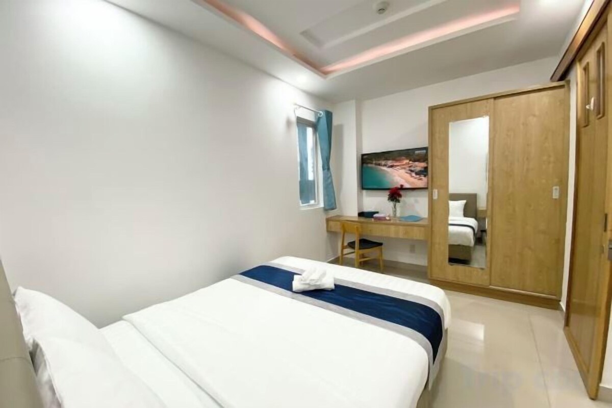 A hotel room with a bed, a desk, a wardrobe, and a mirror.