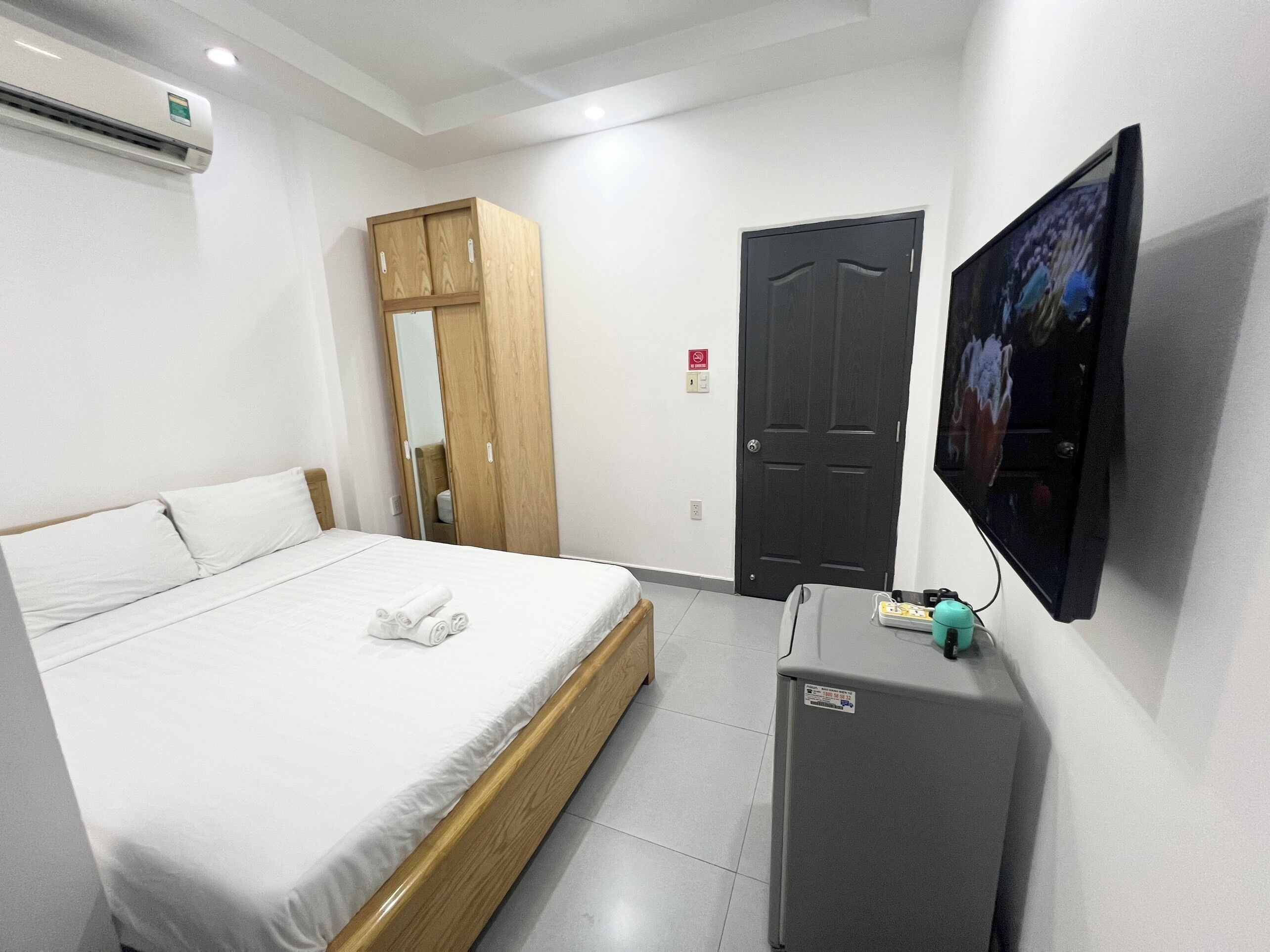 A hotel room with a bed, a wardrobe, a television, and a small refrigerator.