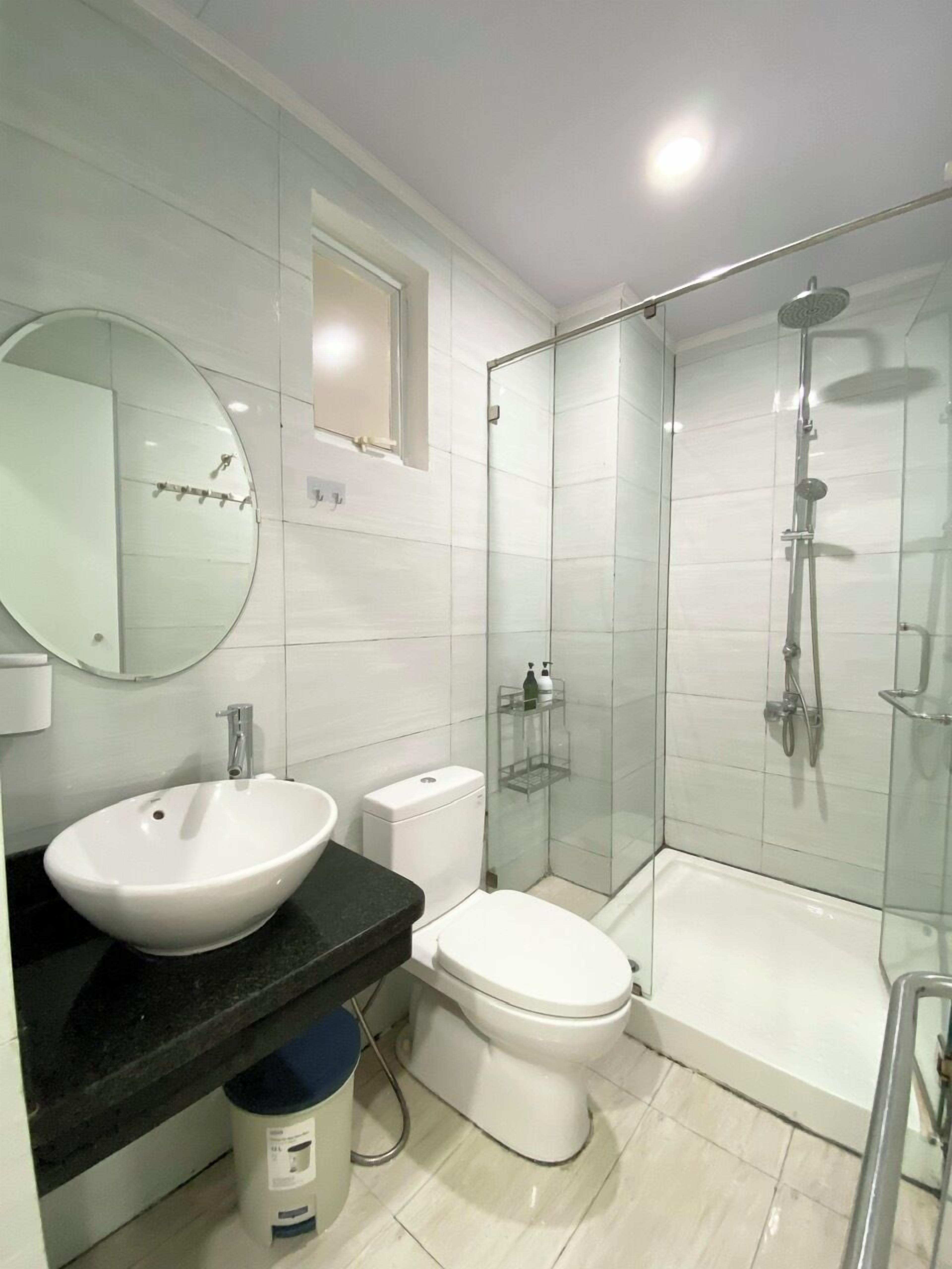 A modern bathroom with a white sink, toilet, and glass-enclosed shower.