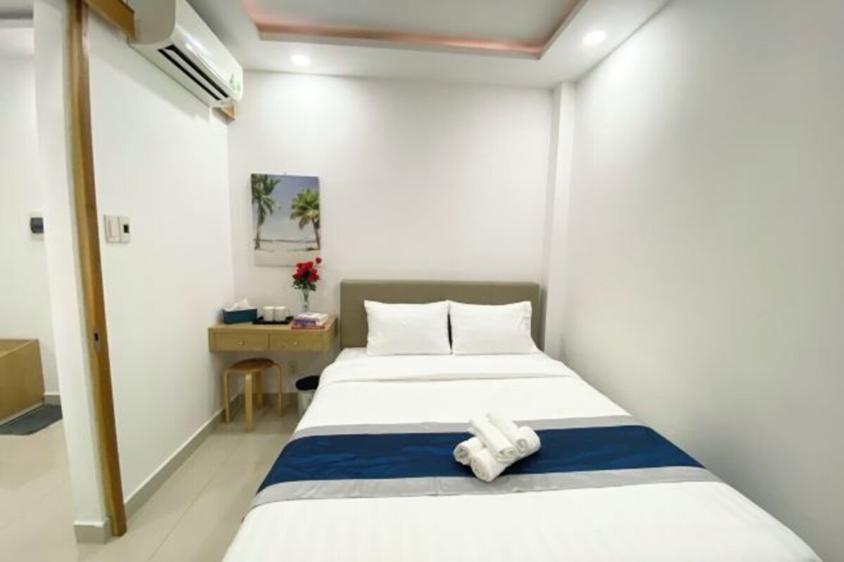 Una habitación de hotel con cama, escritorio, silla y equipo de aire acondicionado.