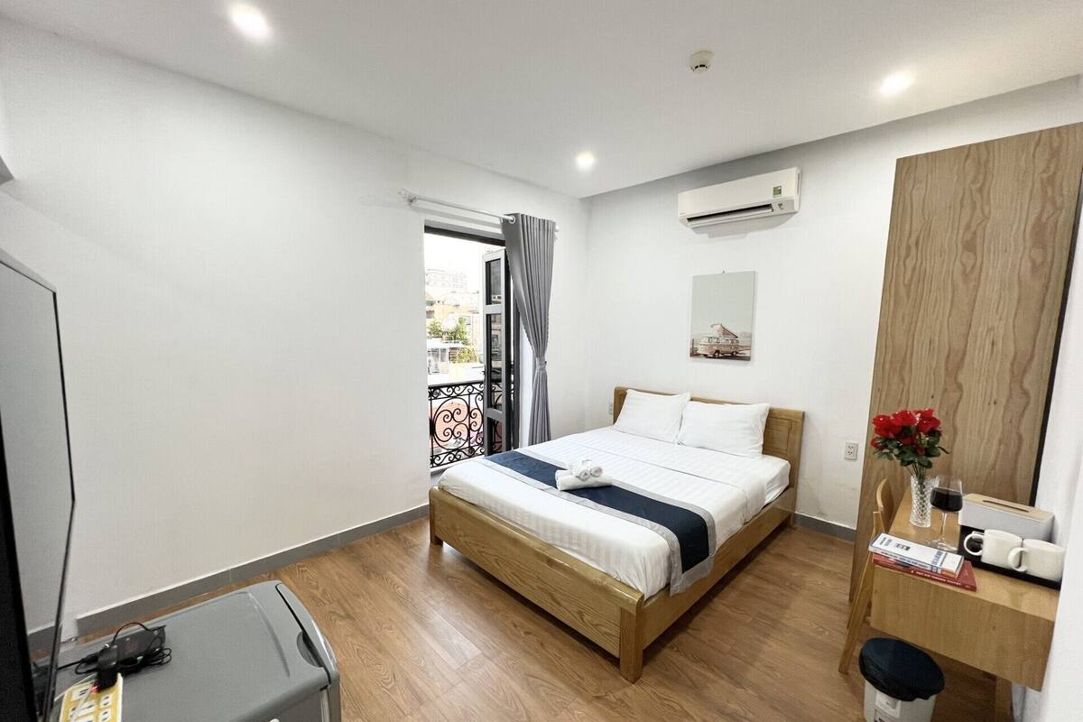 Habitación de hotel con cama, escritorio con espejo, maleta y ventana con cortinas.