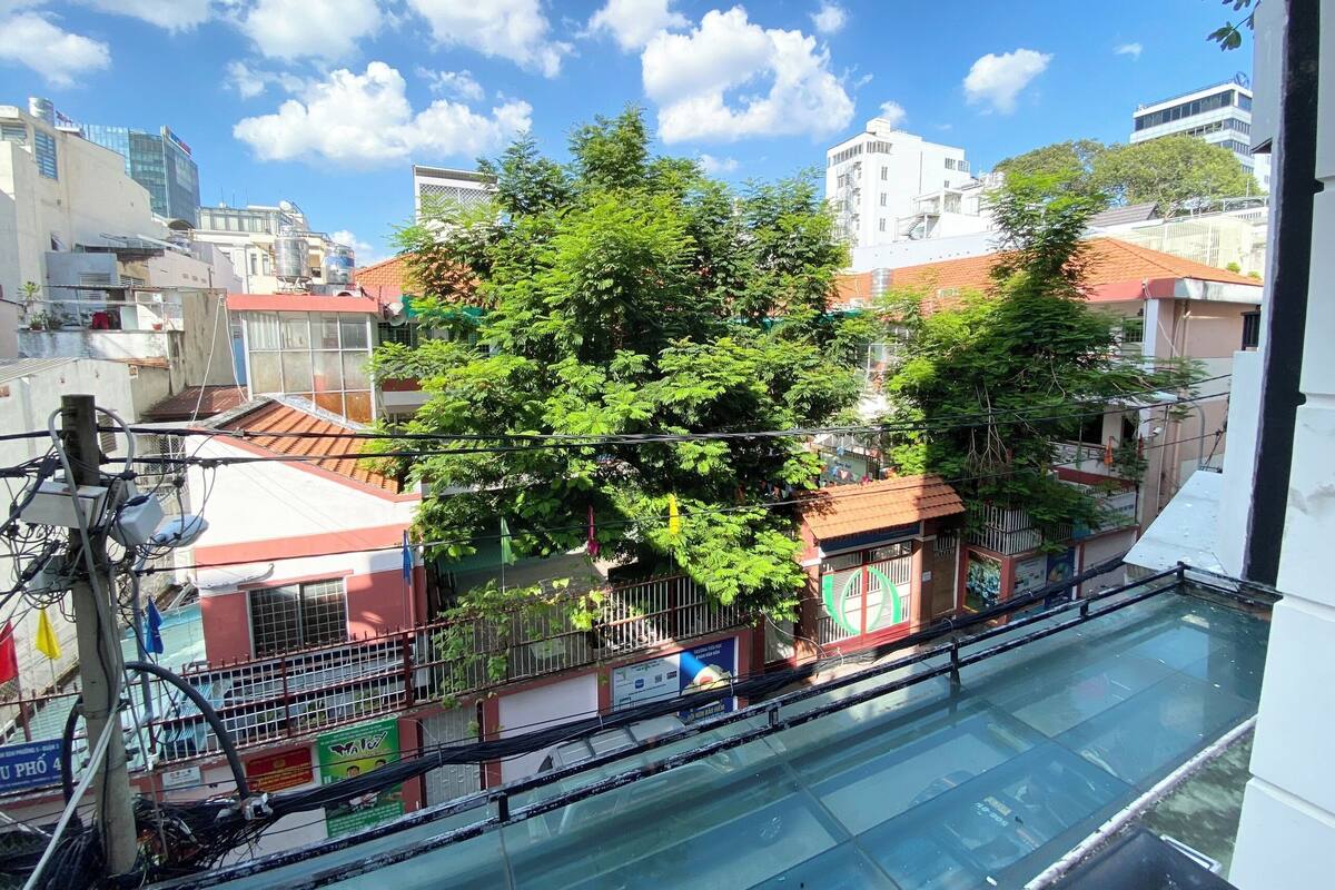 Un barrio residencial con un árbol en primer plano, edificios al fondo y un cielo azul despejado.