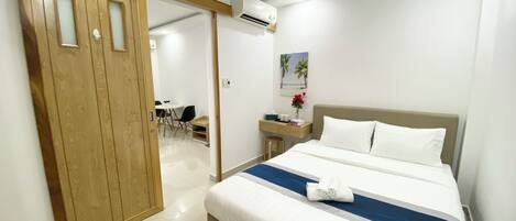 A hotel room with a bed, bedside table, and a desk with chairs.