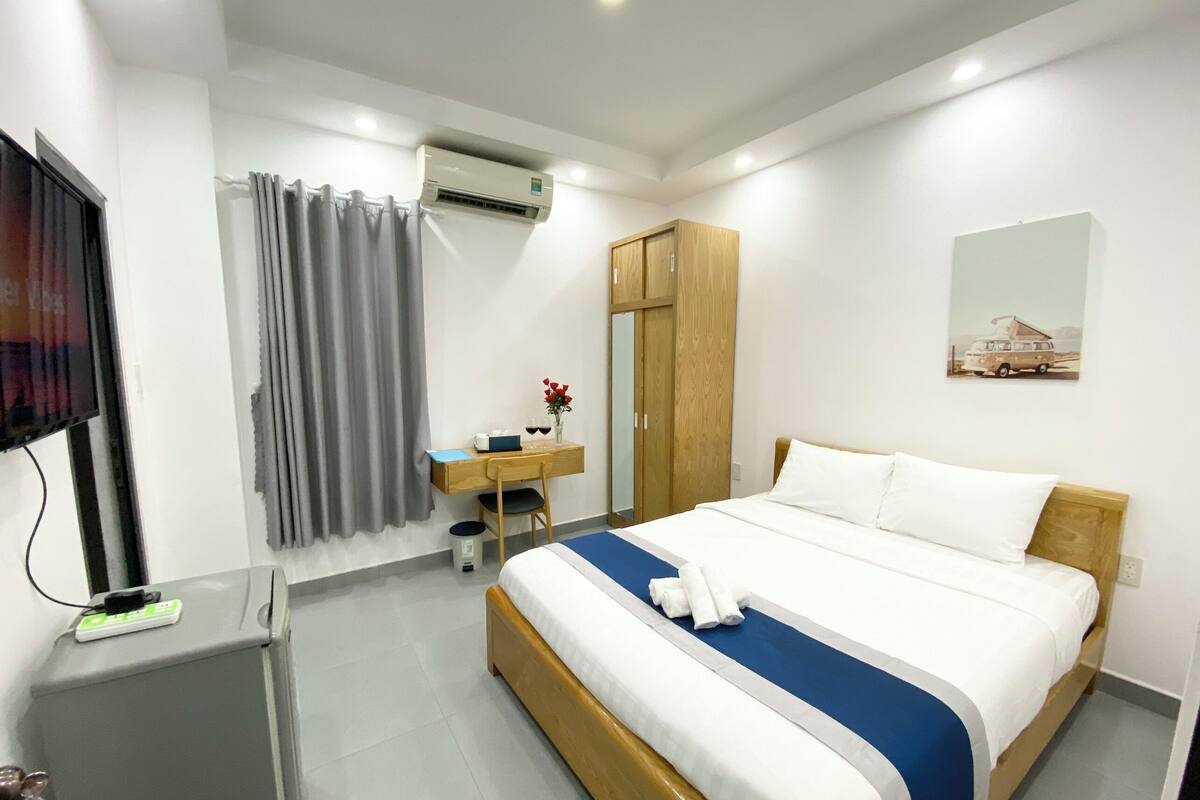 Habitación de hotel con cama, escritorio, armario, aire acondicionado, televisor y un cuadro en la pared.