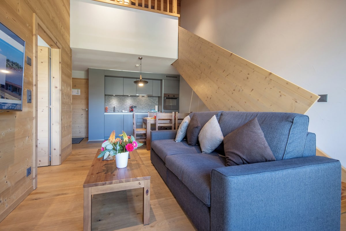 Una sala moderna con sofá, mesa de centro y vistas a la cocina.