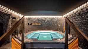 A modern spa with a hot tub, stone walls, and wooden accents. - SWISSPEAK Resorts by Pierre & Vacances Premium Vercorin (Chalais)
