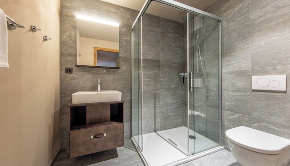 Une salle de bain moderne avec une douche à parois de verre, un lavabo blanc et des toilettes.