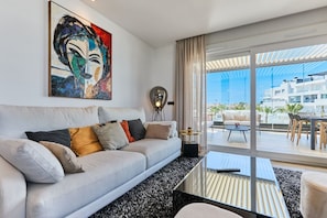 A modern living room with a sofa, a coffee table, and a painting on the wall.