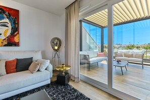 Una sala de estar moderna con un sofá, una lámpara de pie y un ventanal con vistas a un balcón.