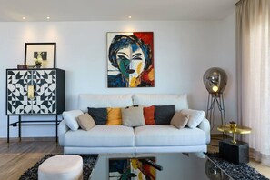Een woonkamer met een bank, een kast, een schilderij en een vloerlamp.