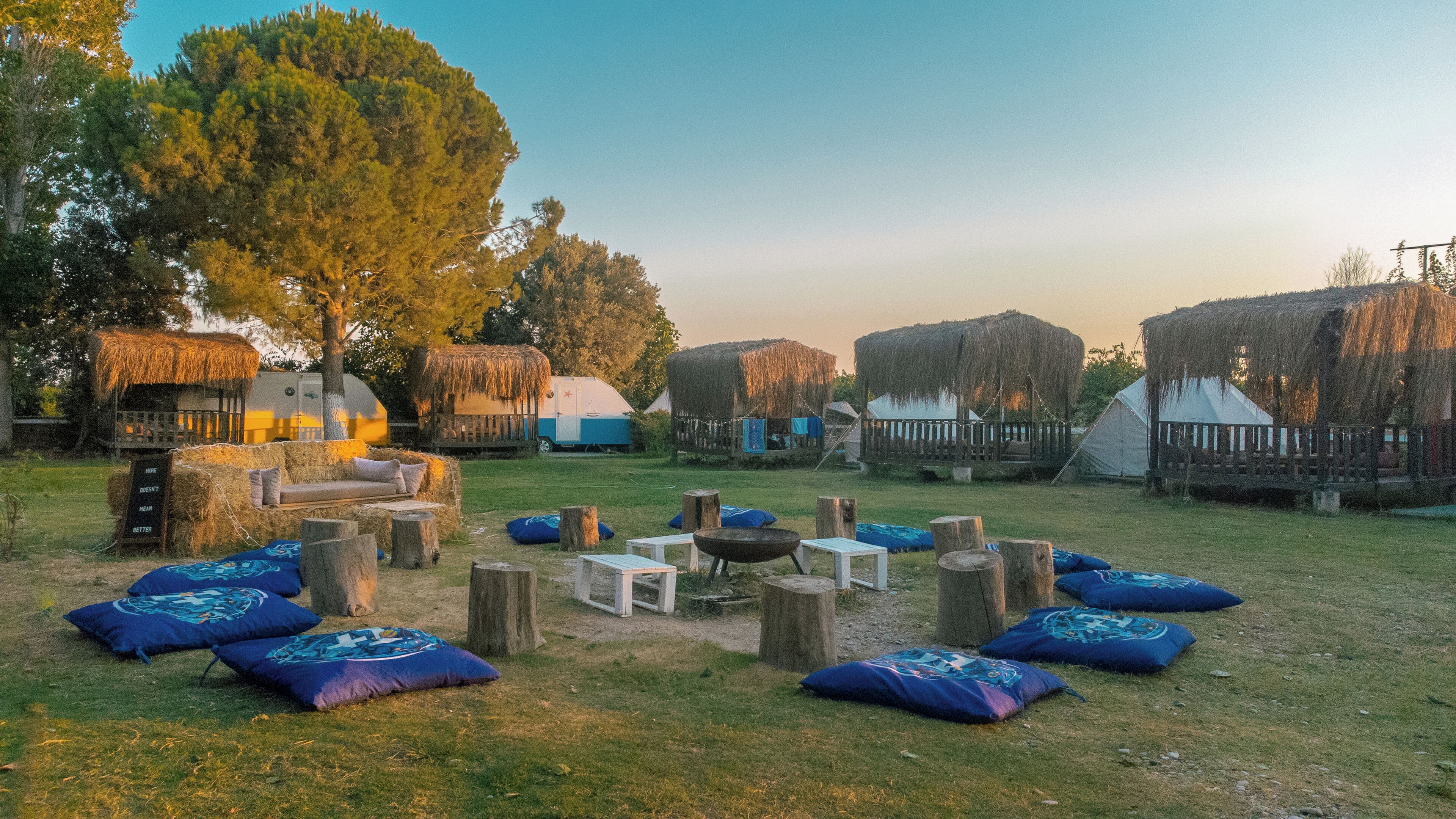 Un camping con tiendas de techo de paja, un hogar central y zonas de estar dispersas.