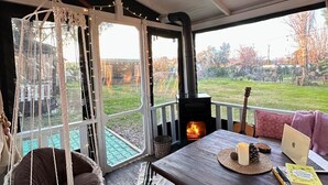 Um quarto aconchegante com uma mesa de madeira, uma cadeira suspensa e vista para um gramado.