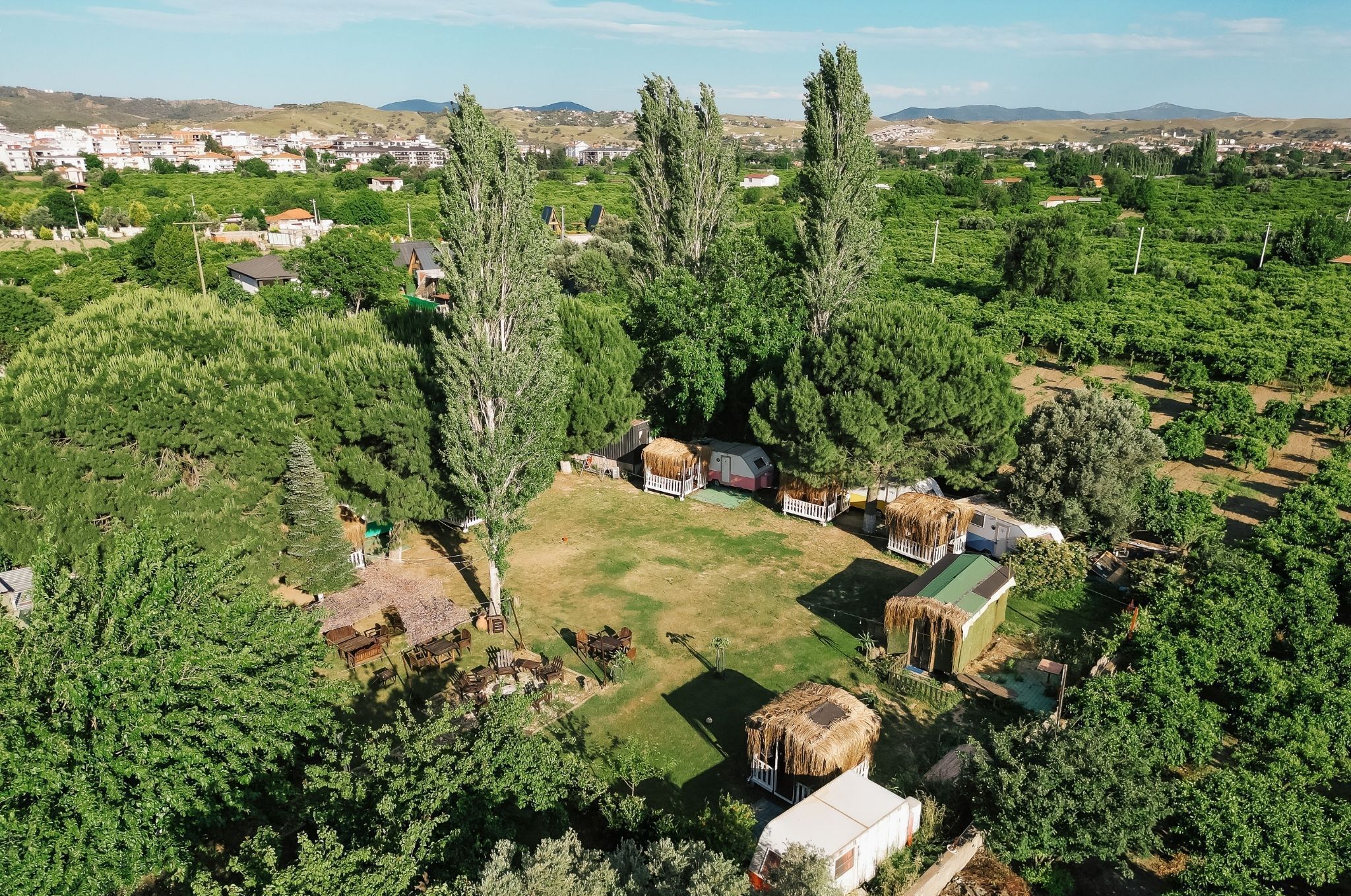 An aerial view of a rural area with a small cluster of houses surrounded by dense greenery and trees.