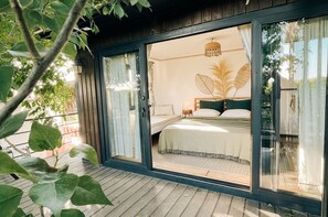 A bedroom with a bed, a nightstand, and a large window. - Mona Glamping Caravan Suites (Seferihisar)