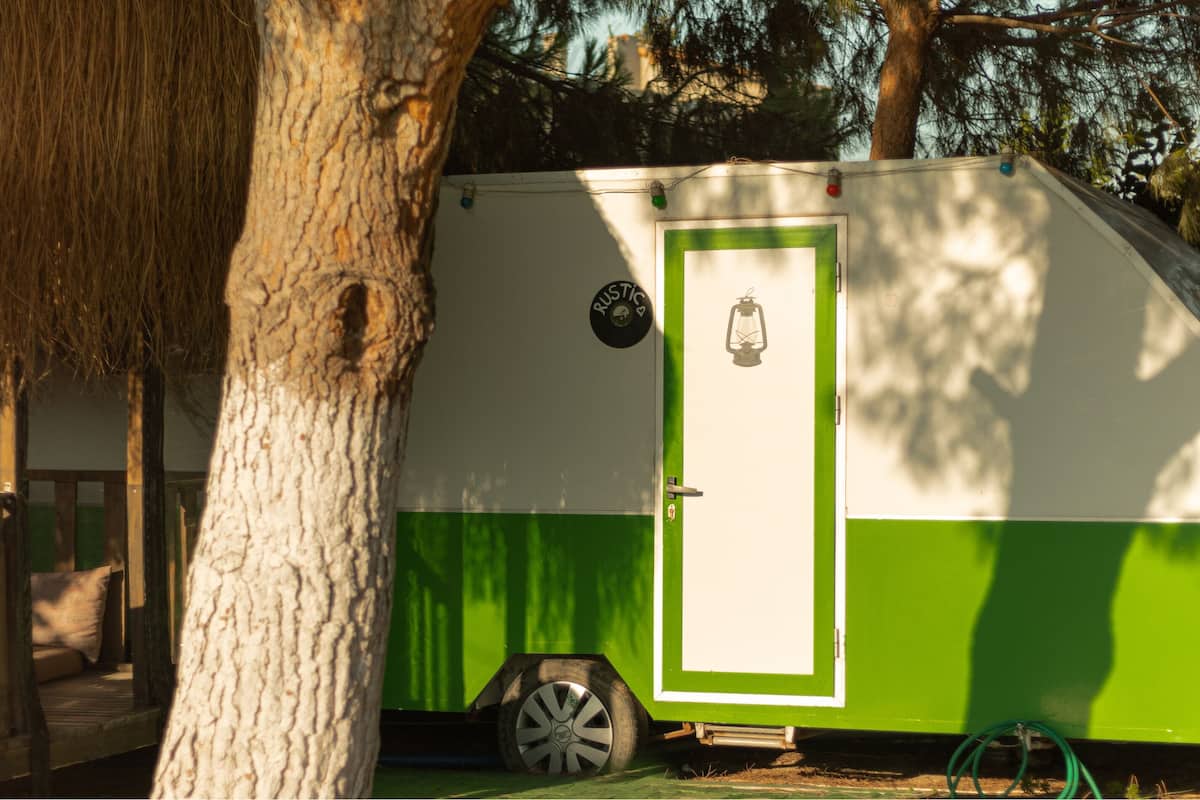 A green and white RV with a door, a wheel, and a small sign on the side.