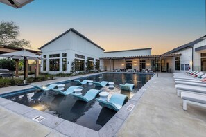 Piscina com espreguiçadeiras e área de estar coberta.