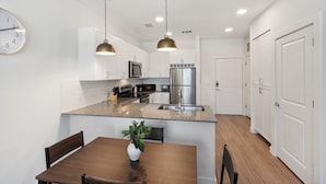 A modern kitchen with white cabinets, stainless steel appliances, and a granite countertop. - Stunning Austin Oasis I Properties by Preston (Austin)