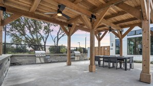 An outdoor patio with a grill, seating area, and a view of the surrounding landscape. - Stunning Austin Oasis I Properties by Preston (Austin)
