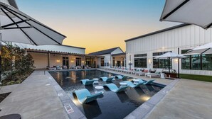 A pool area with lounge chairs and umbrellas, surrounded by buildings with large windows. - Spectra Parks 7310, Stunning Austin Oasis (Austin)