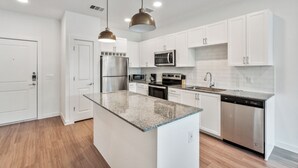 A modern kitchen with white cabinets, stainless steel appliances, granite countertops, and pendant lighting. - Spectra Parks 7310, Stunning Austin Oasis (Austin)