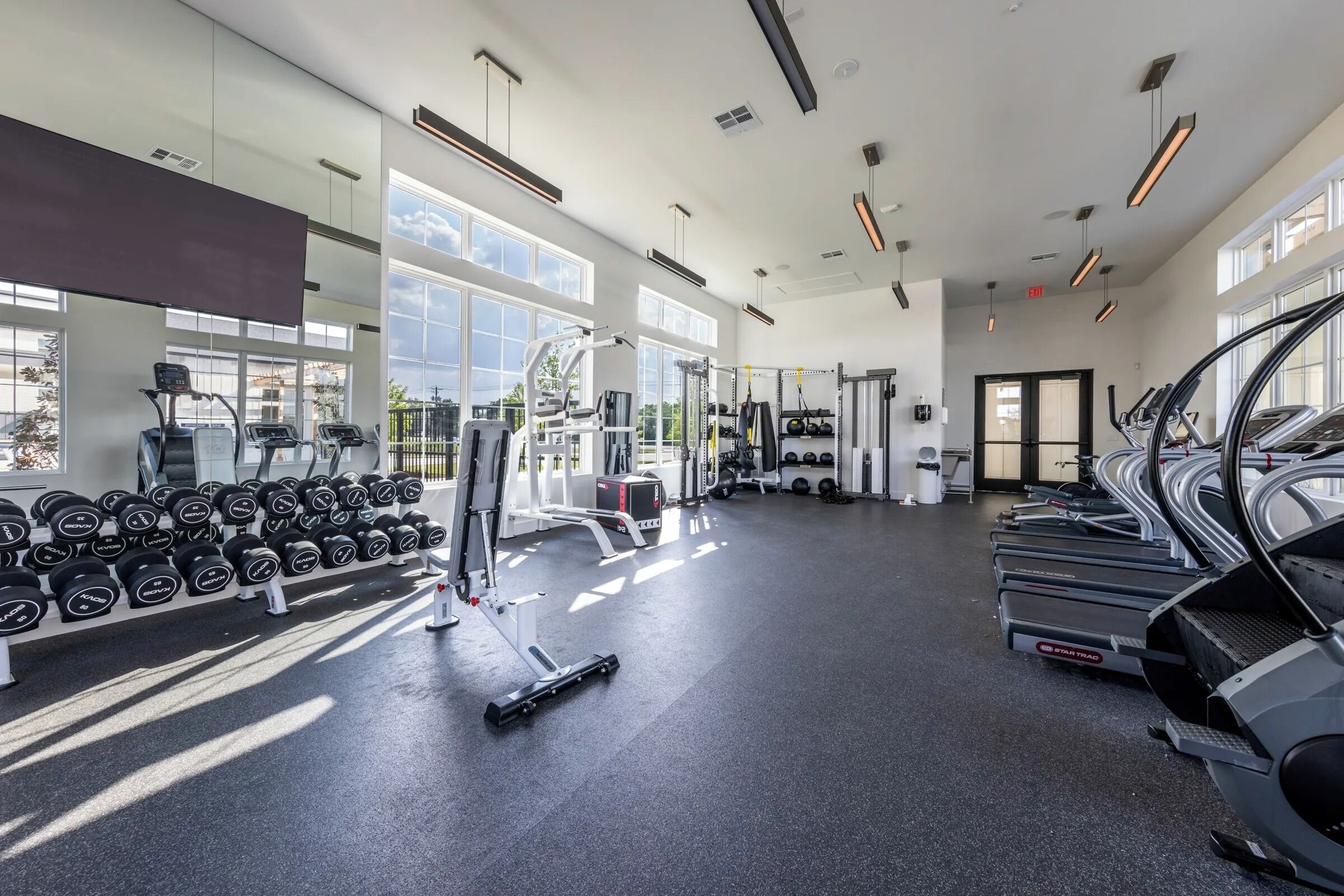 Een ruime fitnessruimte met loopbanden, krachttrainingsapparaten en gewichten.
