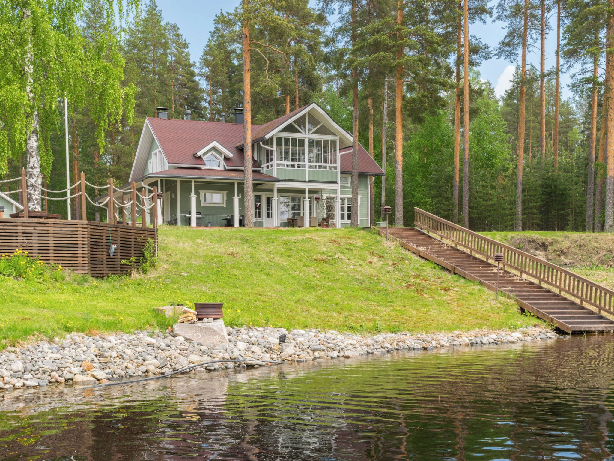 Un chalet au bord du lac, doté d’un quai et d’un escalier en bois menant à une terrasse.